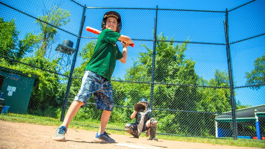 Boy swing baseball bat during summer camp game