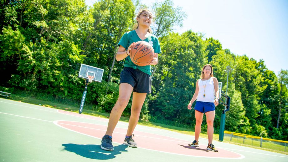 Girl holds basketball during summer camp game