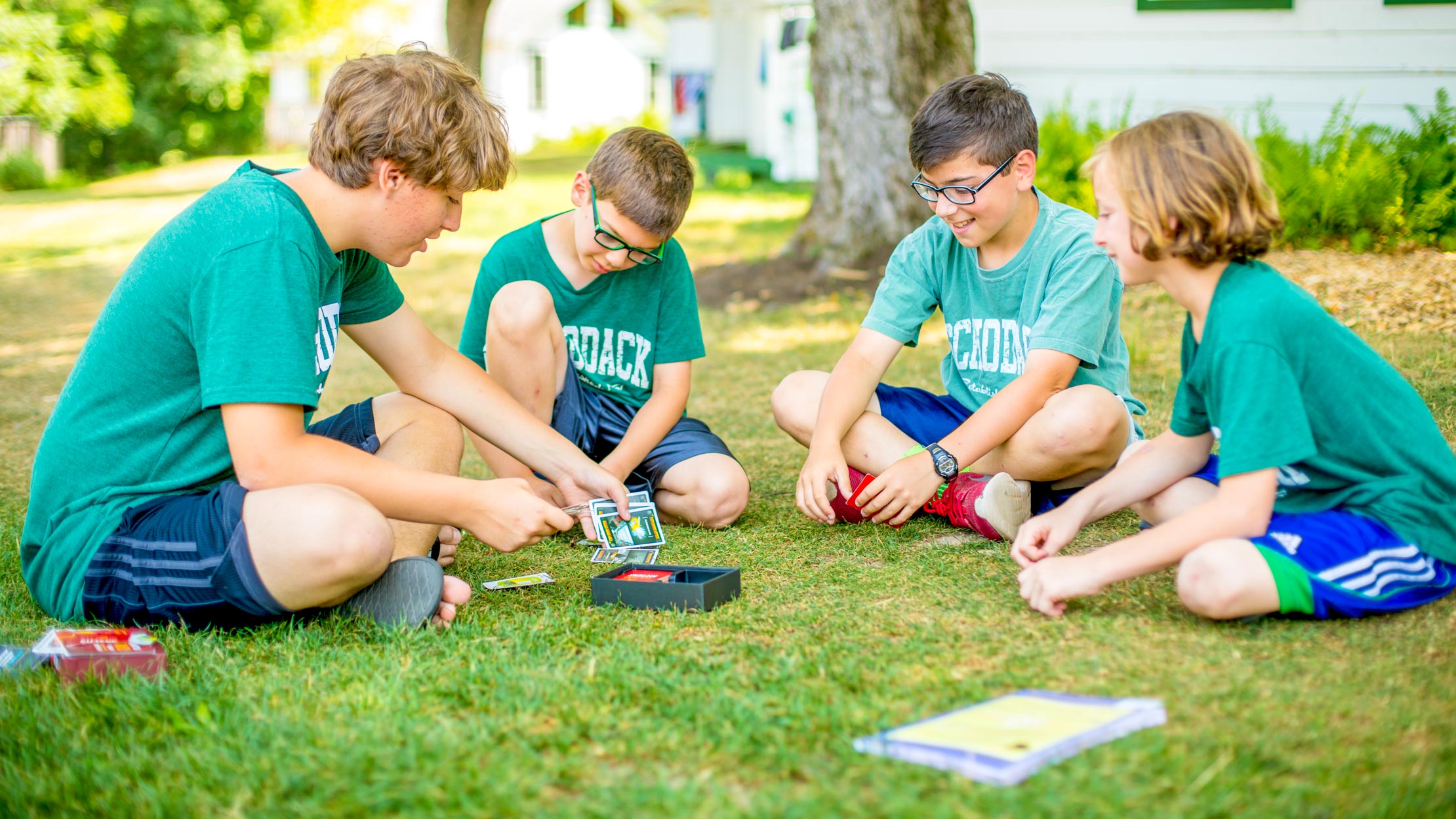 Boys playing cards on the grass at summer camp