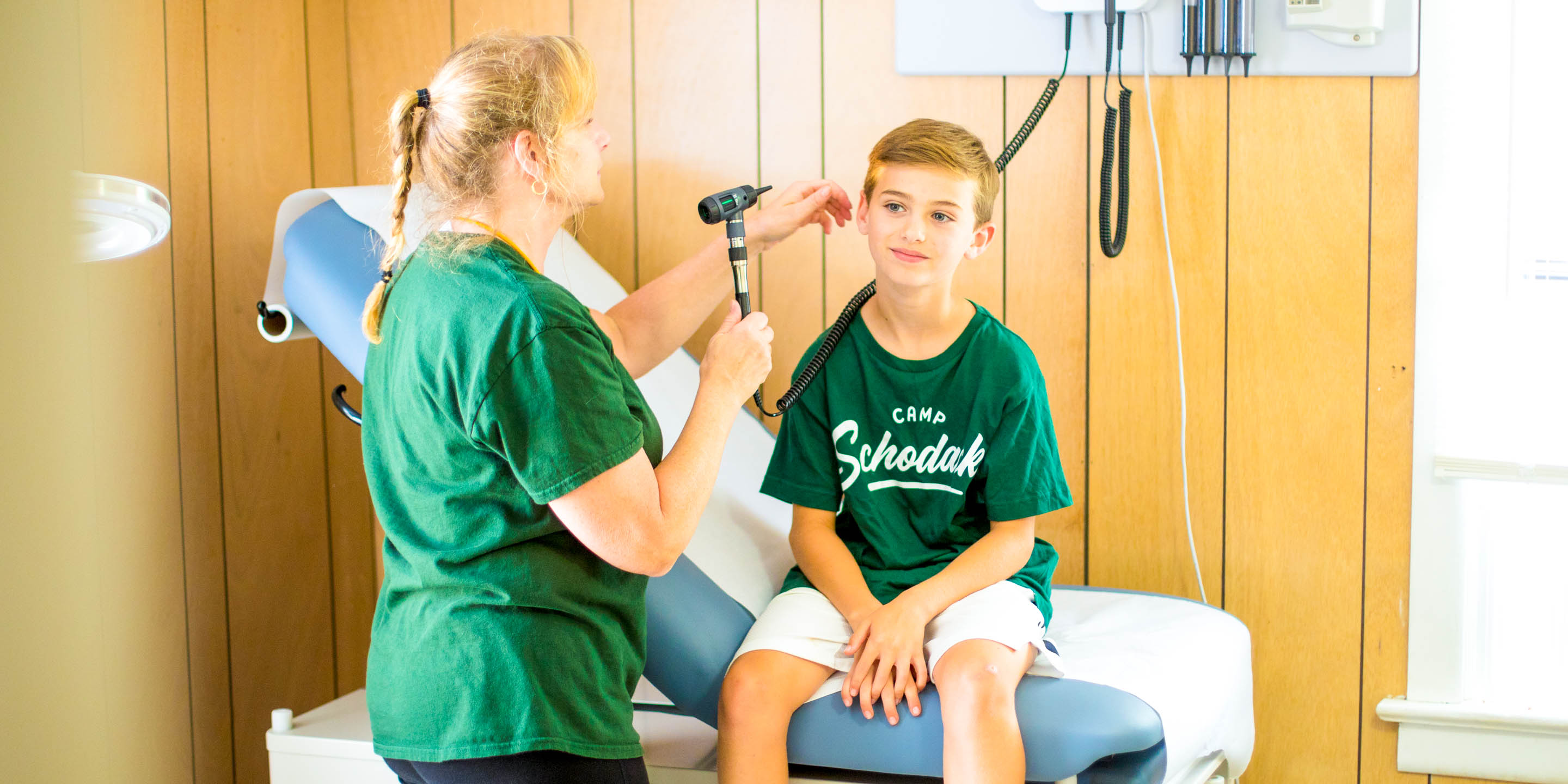 Summer camp nurse performs health check-up on camper