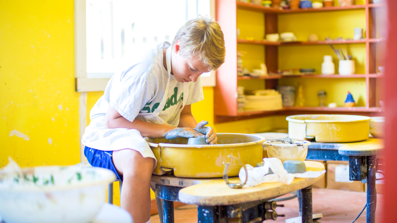 Camper works at pottery wheel