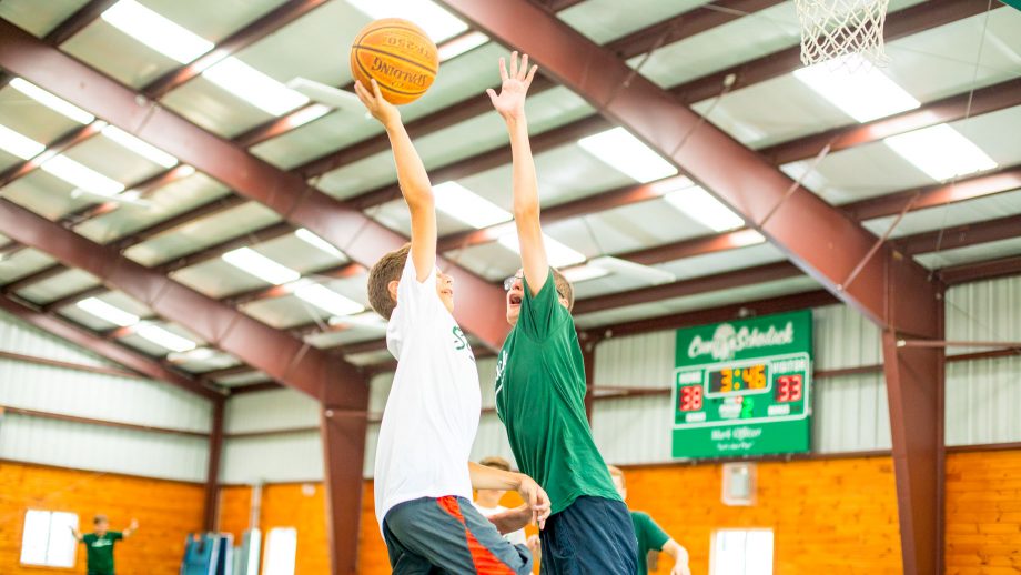 Camper jumps to block shot on hoop during basketball