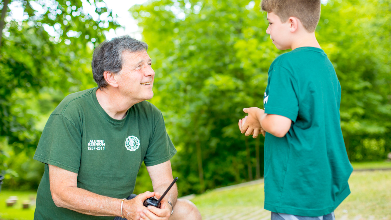 Camp director bends down to talk to camper