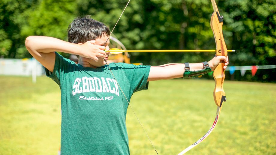 Boy draws bow during summer camp archery