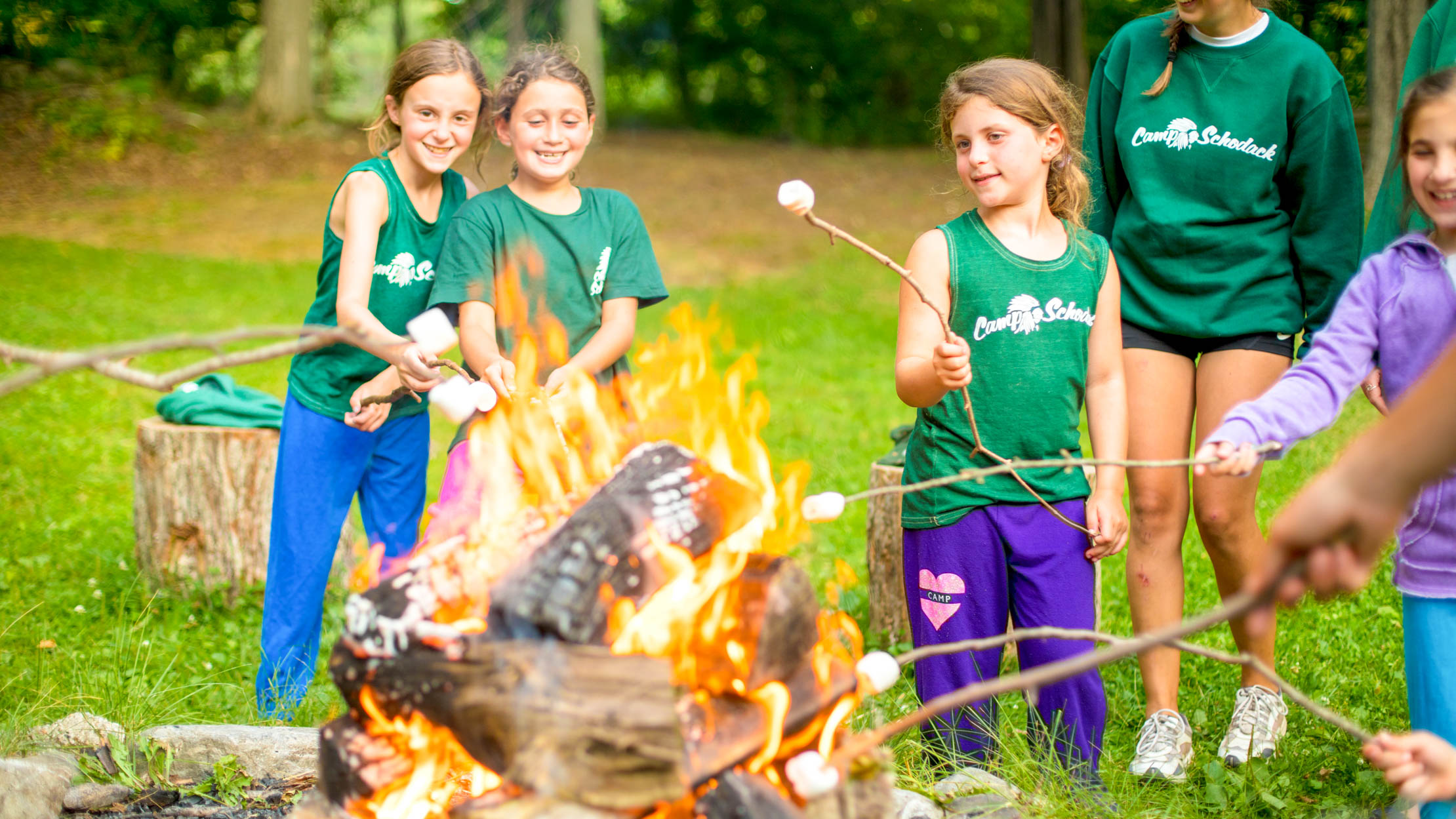 Campers roast marshmallows over an outdoor fire