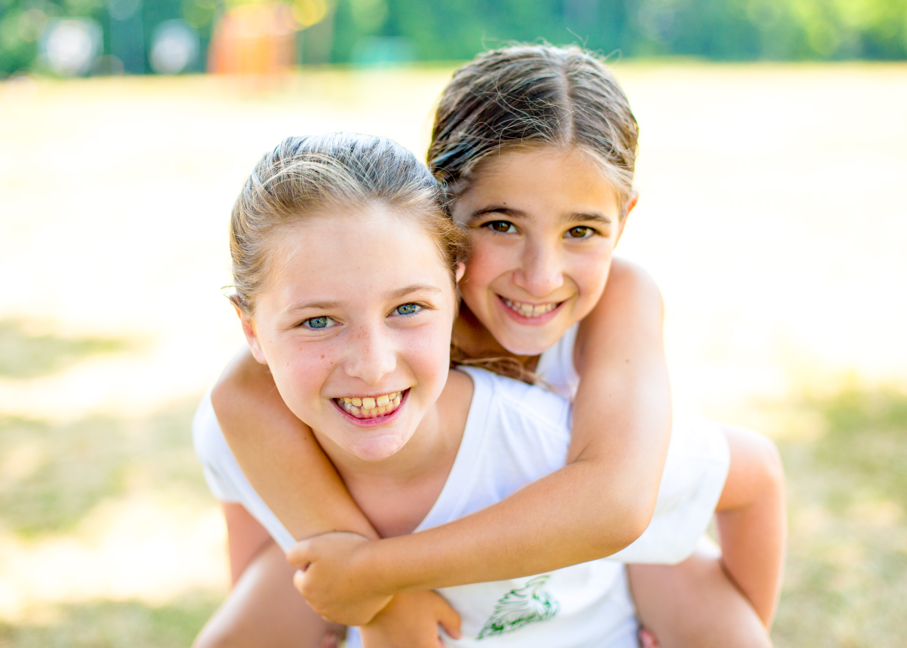 Young girl gives another girl a piggyback ride