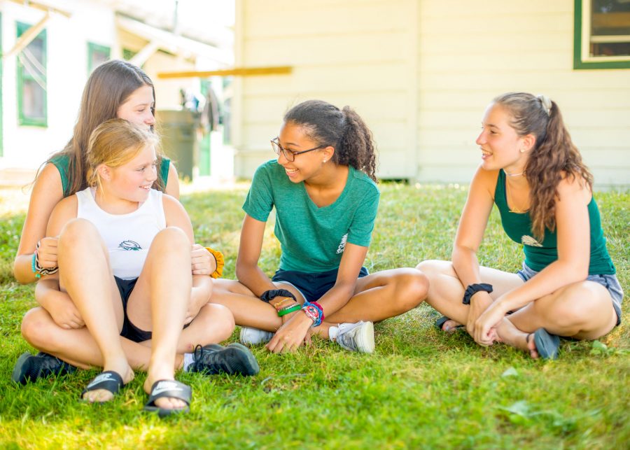 Girls sit on the grass, laughing and smiling