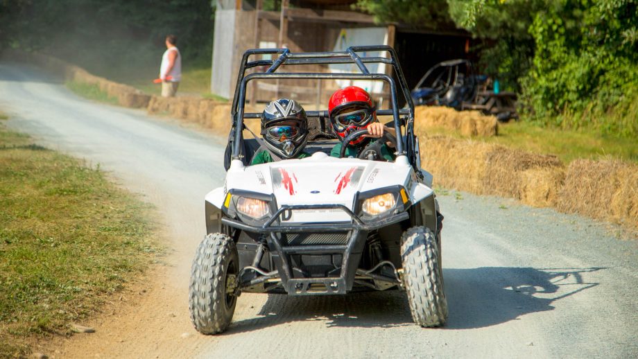 Campers drive go-kart around summer camp track