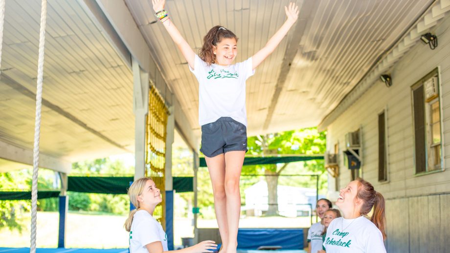 Smiling girl raises arms on balance beam