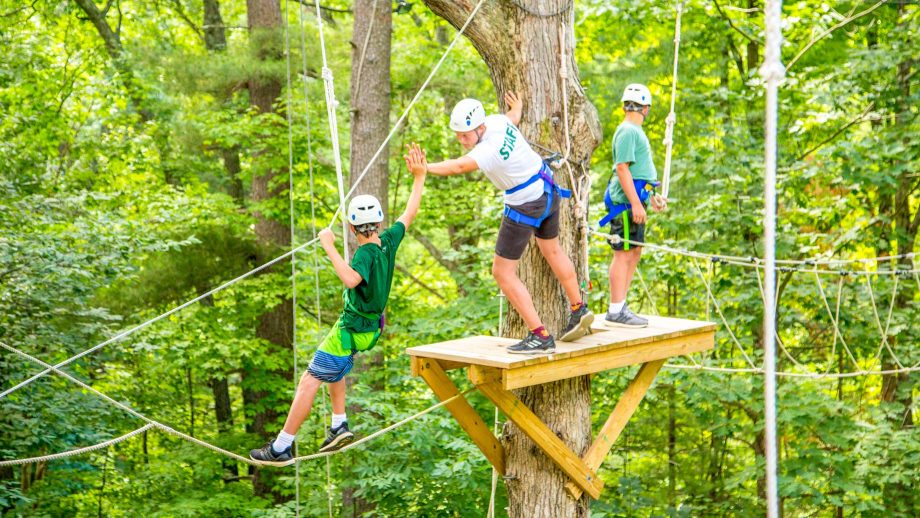 Camper and staff member high five on high ropes course