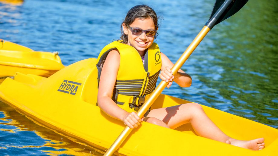 Smiling camper paddles yellow kayak