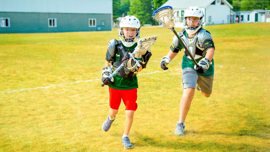 Boys run during summer camp lacrosse game