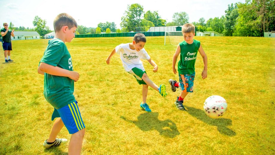 Boy kicks soccer ball during summer camp game