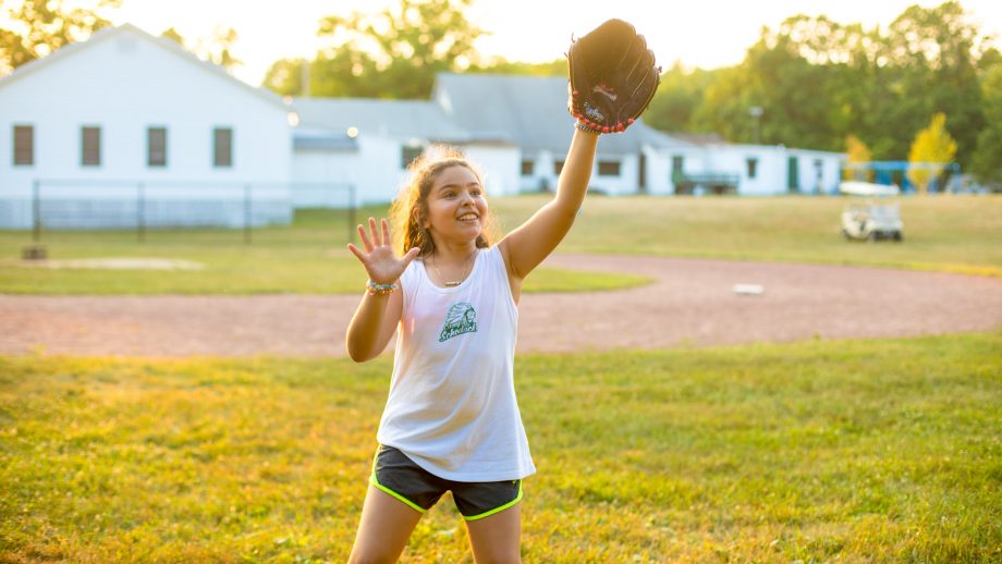 Girl prepares to catch softball during summer camp game