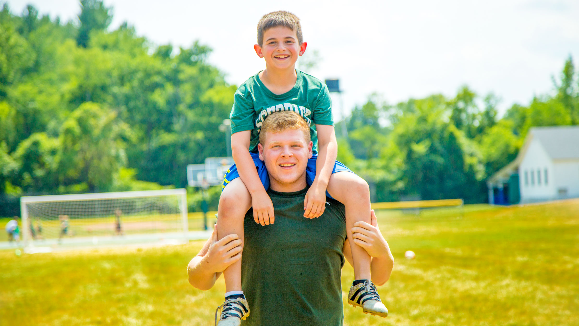 Counselor carries camper on his shoulders