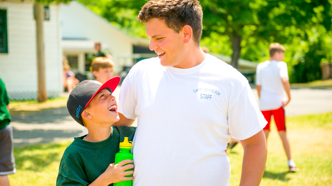 Boy smiles up at summer camp counselor