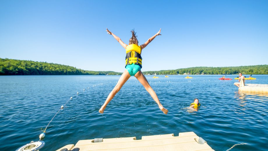 Camper jumps off dock in starfish pose