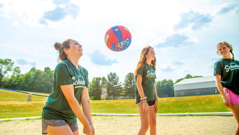 Girl serves volleyball during summer camp game