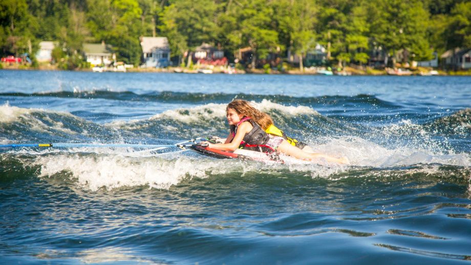 Camper lies on stomach while wakeboarding