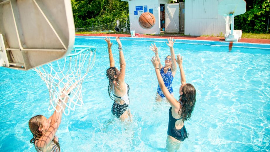 Campers play water basketball in summer camp pool