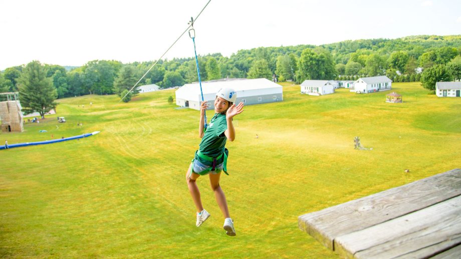 Girl turns to wave at beginning of zip line