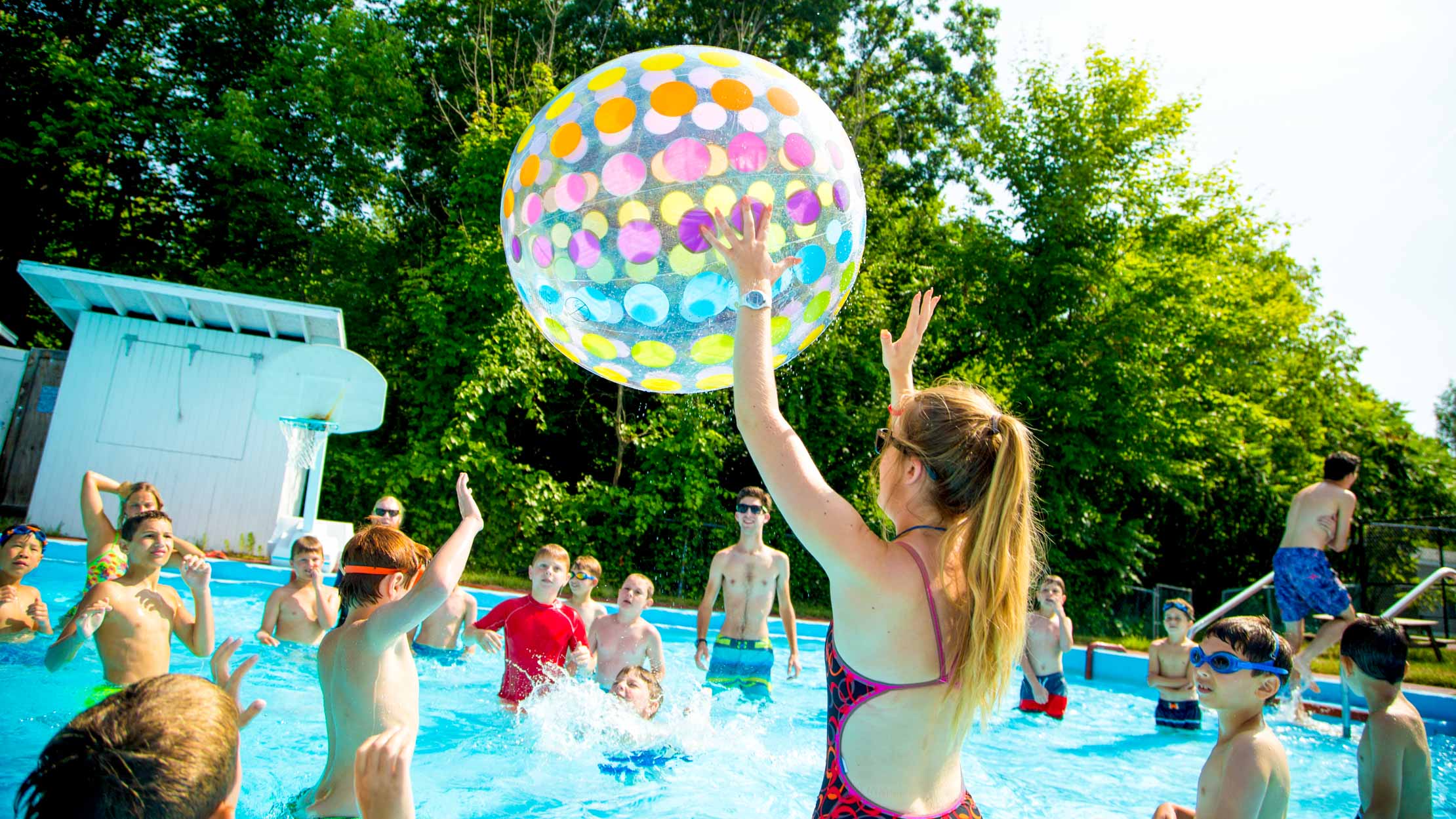 Campers play with inflatable ball in swimming pool