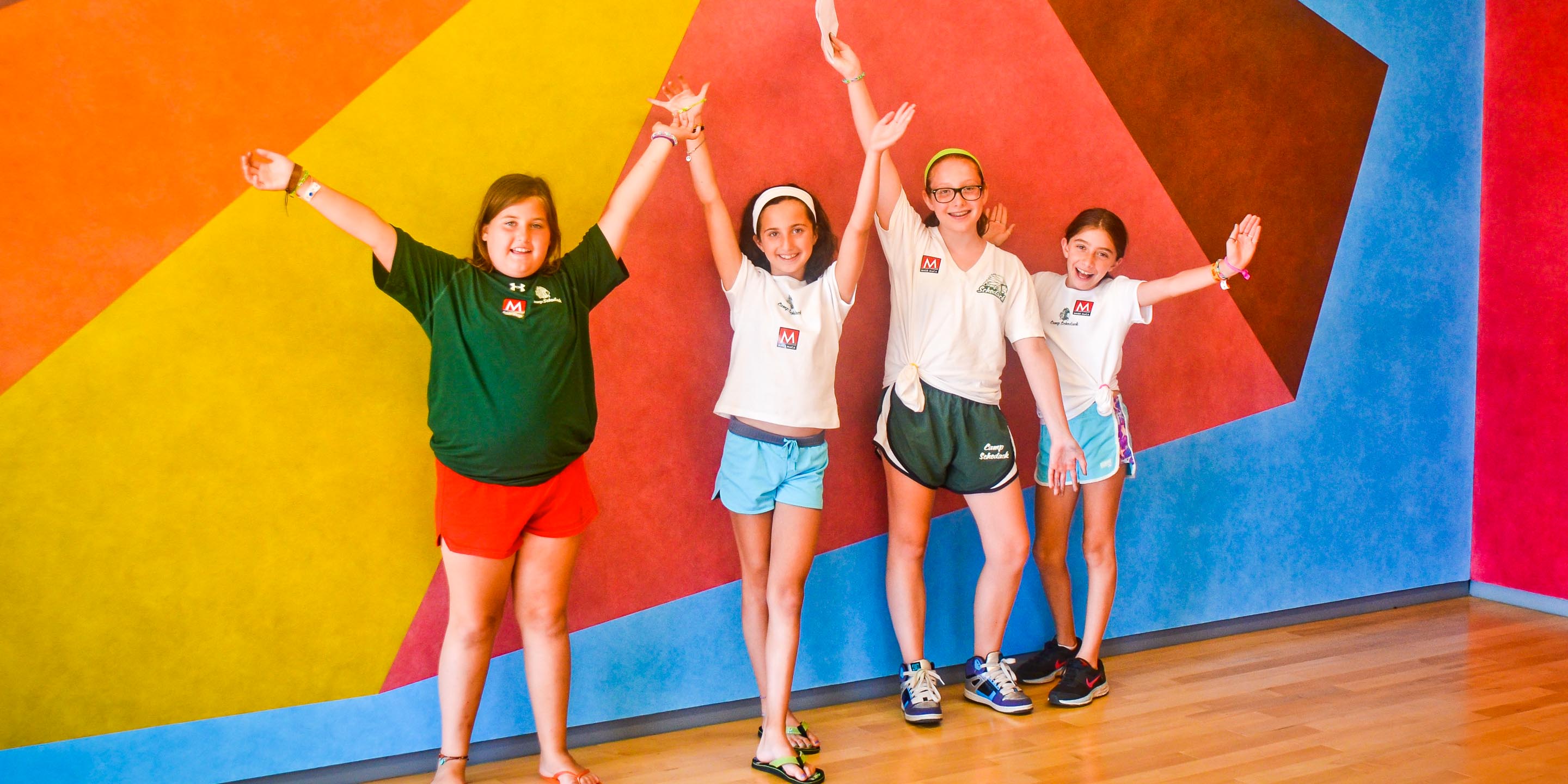 Girls pose in front of colorful wall during camp field trip