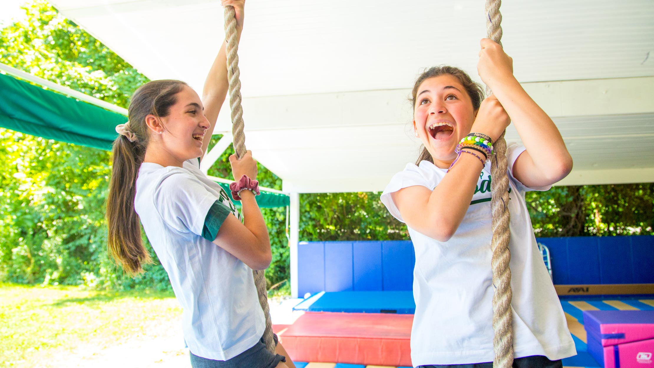 Smiling girls hang onto vertical ropes
