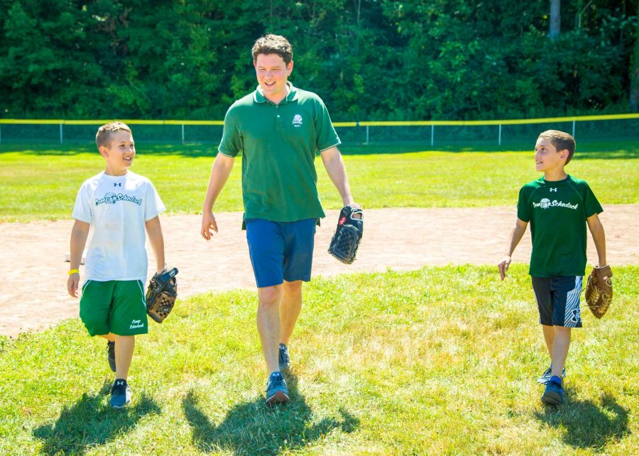 Matt walks beside campers on camp baseball field