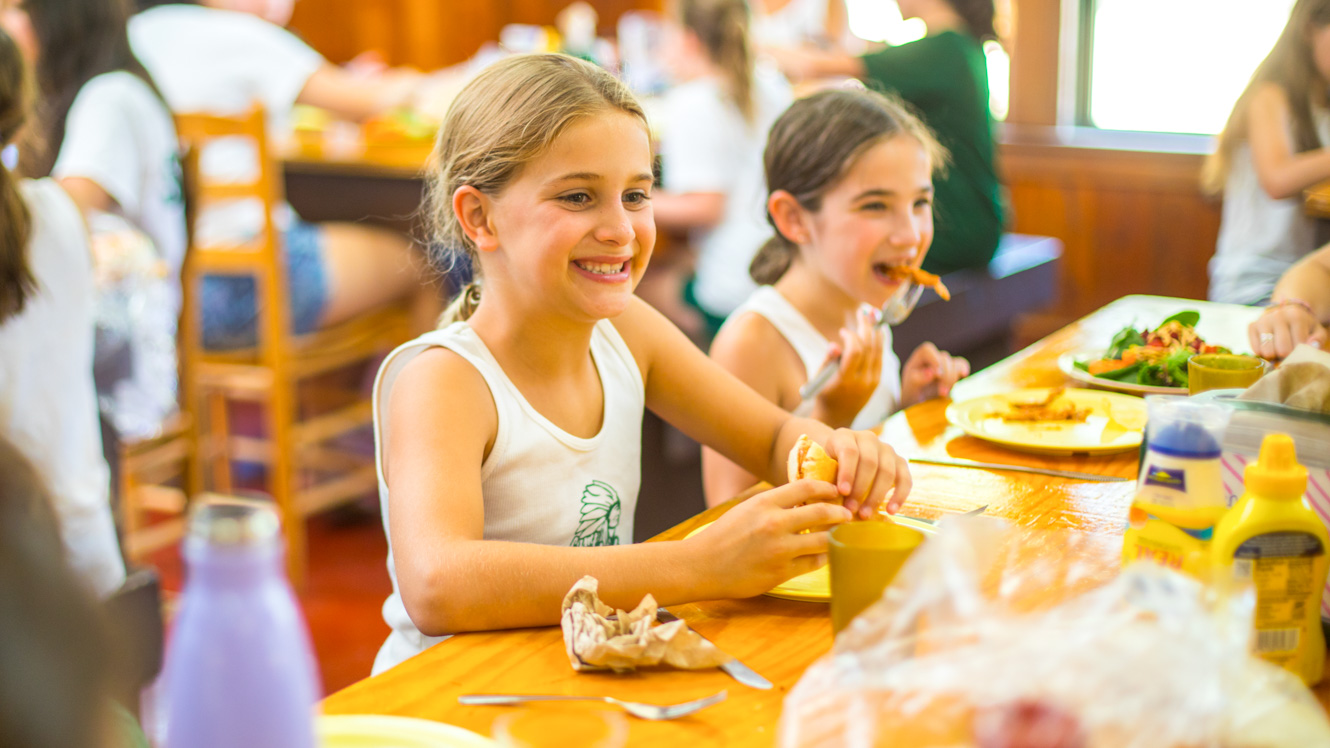 Camper smiles while eating lunch in dining hall