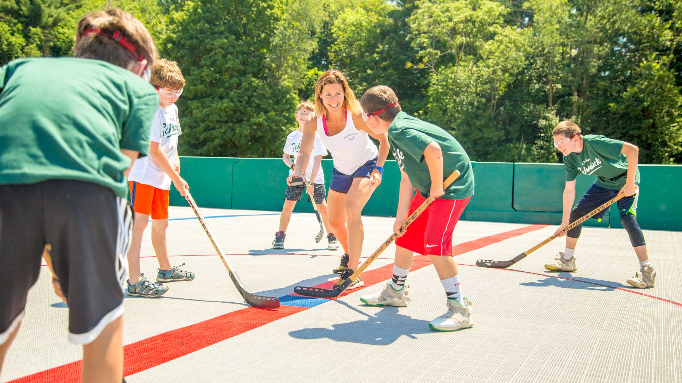 Staff member preps campers for street hockey game