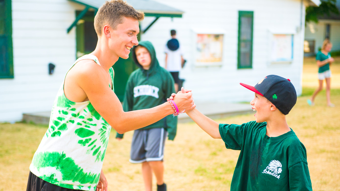 Counselor shakes hands with camper